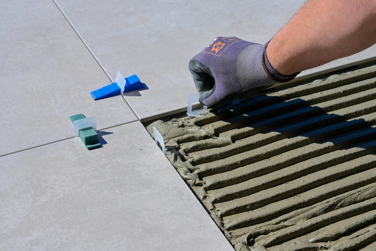Un carreleur place un croisillon de carrelage